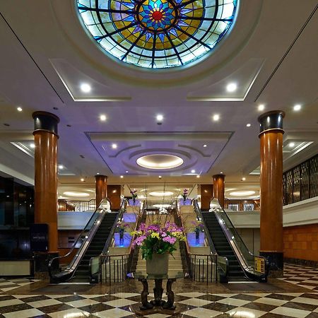 Seri Pacific Hotel Kuala Lumpur Exterior photo The photo depicts an elegant hotel lobby featuring a large stained glass ceiling that adds a colorful touch to the space. The lobby has polished marble flooring with a checkerboard pattern. In the center, there is a beautiful arrangement of flowers i