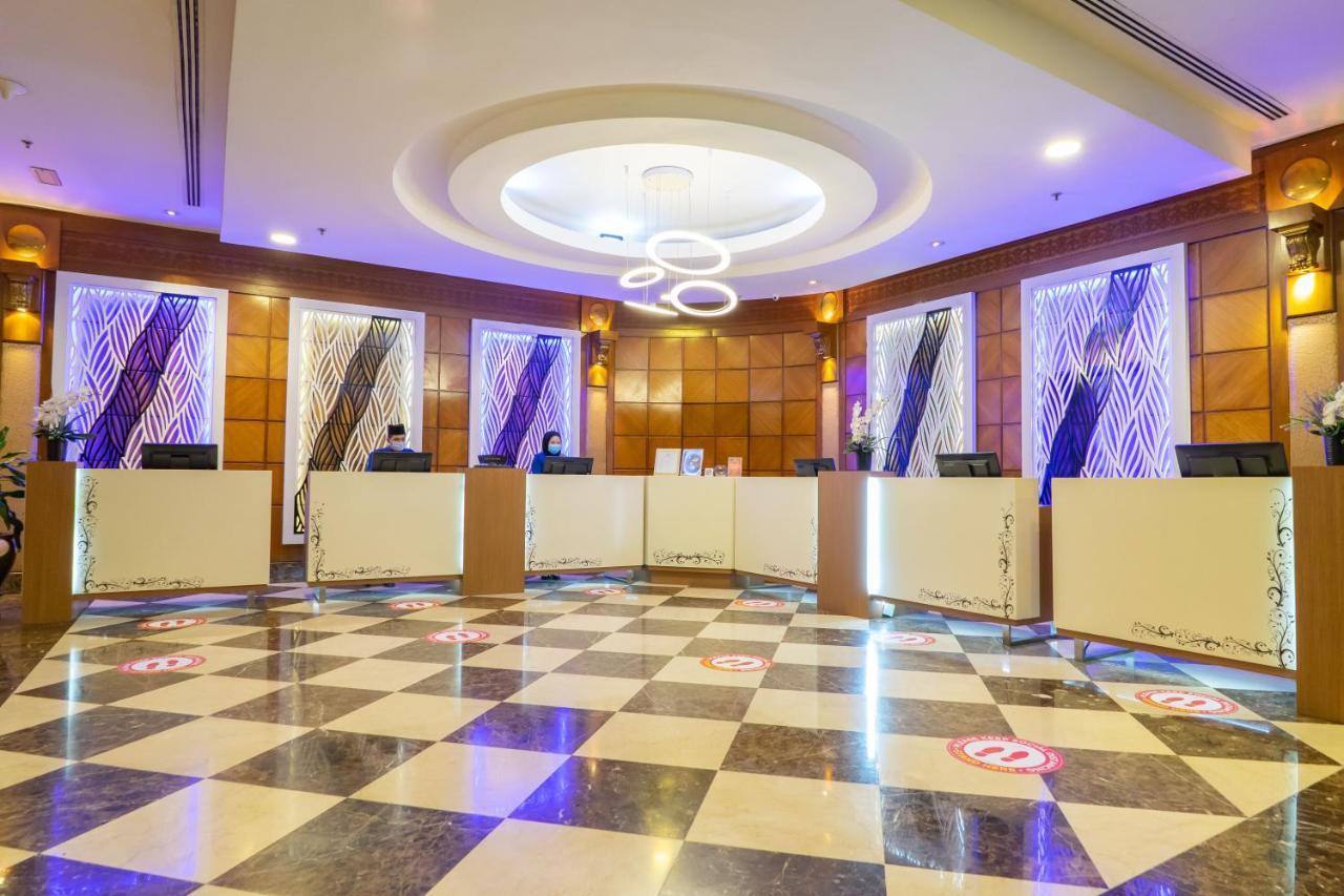 Seri Pacific Hotel Kuala Lumpur Exterior photo The photo shows a modern reception area with a stylish design. There are multiple reception desks arranged in a semi-circle, each with a computer setup. The flooring features a black and white checkered pattern, adding elegance to the space. The wall