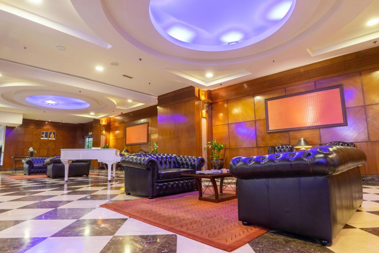 Seri Pacific Hotel Kuala Lumpur Exterior photo The photo shows a spacious and elegantly designed lobby area. It features luxurious black leather sofas arranged around a coffee table, creating a welcoming sitting area. The floor has a striking black and white checkered pattern, complemented by war