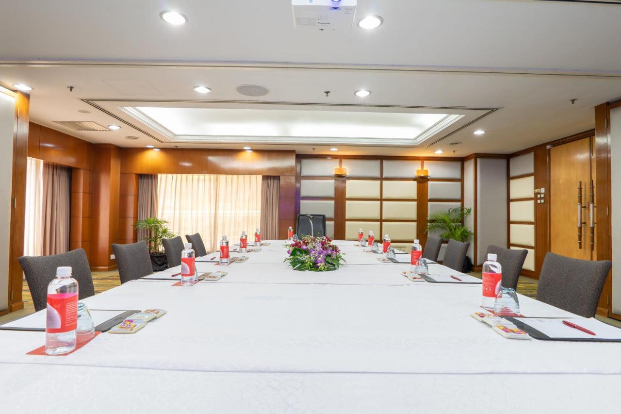 Seri Pacific Hotel Kuala Lumpur Exterior photo The photo shows a well-arranged conference room. In the center, there's a large rectangular table covered with a white tablecloth. Surrounding the table are several gray chairs. On the table, there are bottles of water, stationery, and a floral cente