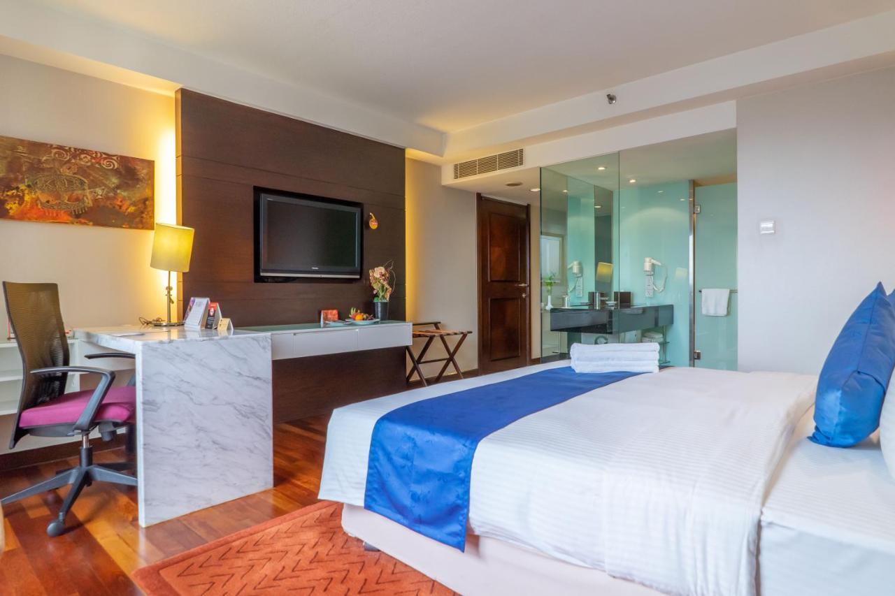 Seri Pacific Hotel Kuala Lumpur Exterior photo The photo shows a modern hotel room featuring:

- A large bed with white linens and a blue accent pillow.
- A flat-screen television mounted on the wall opposite the bed.
- A desk area with a marble top and a chair, providing a work space.
- A small 
