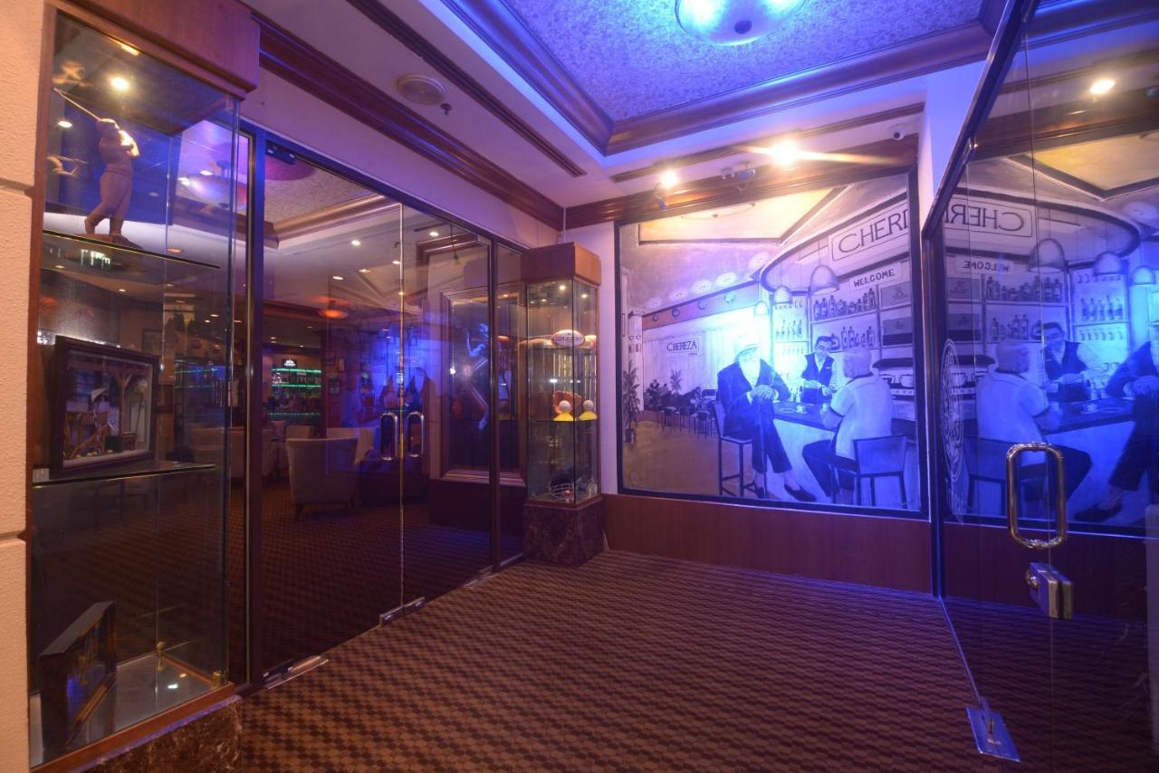 Seri Pacific Hotel Kuala Lumpur Exterior photo The photo shows an interior space featuring a modern design. There are glass walls and doors that create an open and inviting atmosphere. The walls are adorned with large images that depict scenes of people, possibly from a social or dining setting. 