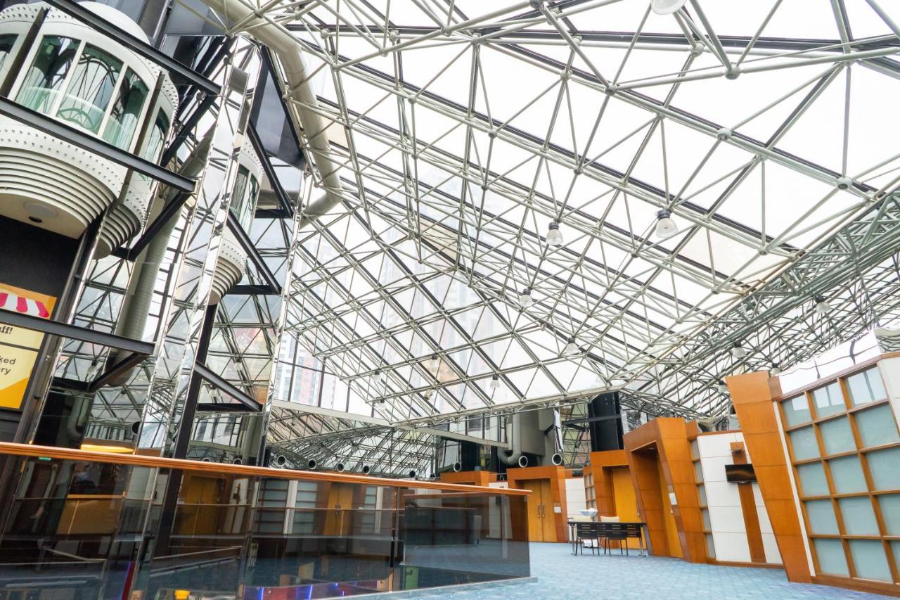 Seri Pacific Hotel Kuala Lumpur Exterior photo The photo depicts a modern architectural interior featuring a spacious atrium with a striking glass and steel roof. The roof consists of a series of geometric triangles, allowing natural light to flood the space. The interior design shows a combinati