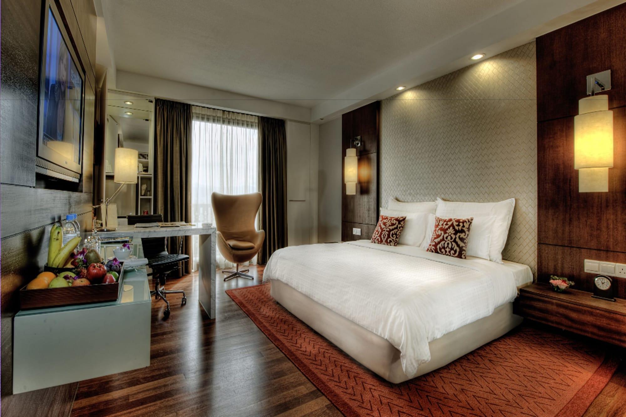 Seri Pacific Hotel Kuala Lumpur Exterior photo The photo shows a modern hotel room. It features a comfortable bed with white linens and decorative pillows. There is a stylish chair beside a small table, which is set with a variety of fresh fruits. The room is well-lit, with large windows allowing