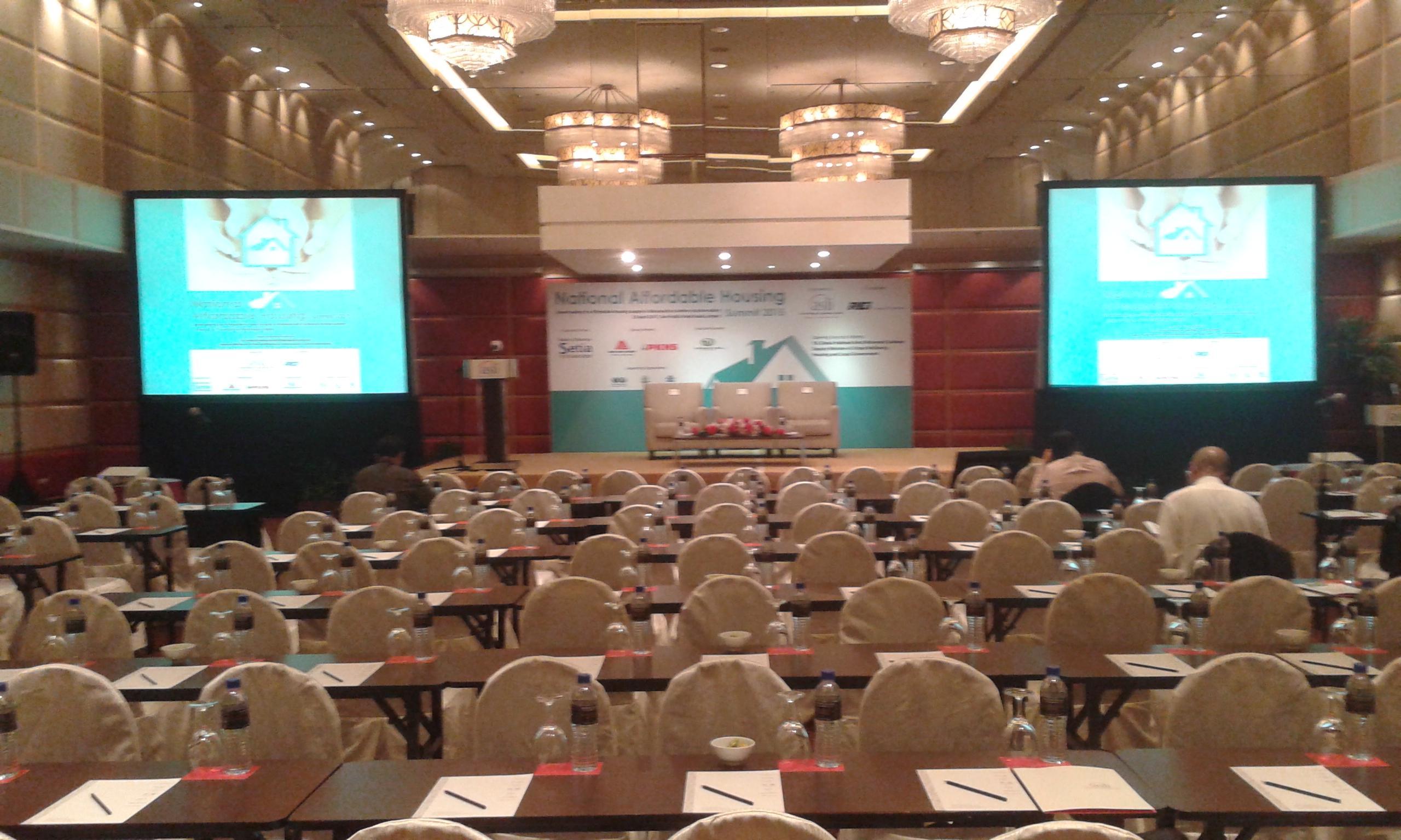 Seri Pacific Hotel Kuala Lumpur Exterior photo The photo shows a conference or seminar room set up for an event. There are many rows of tables and chairs arranged for participants, with each table equipped with a notepad and pen. In the front, there is a stage area with screens on either side dis