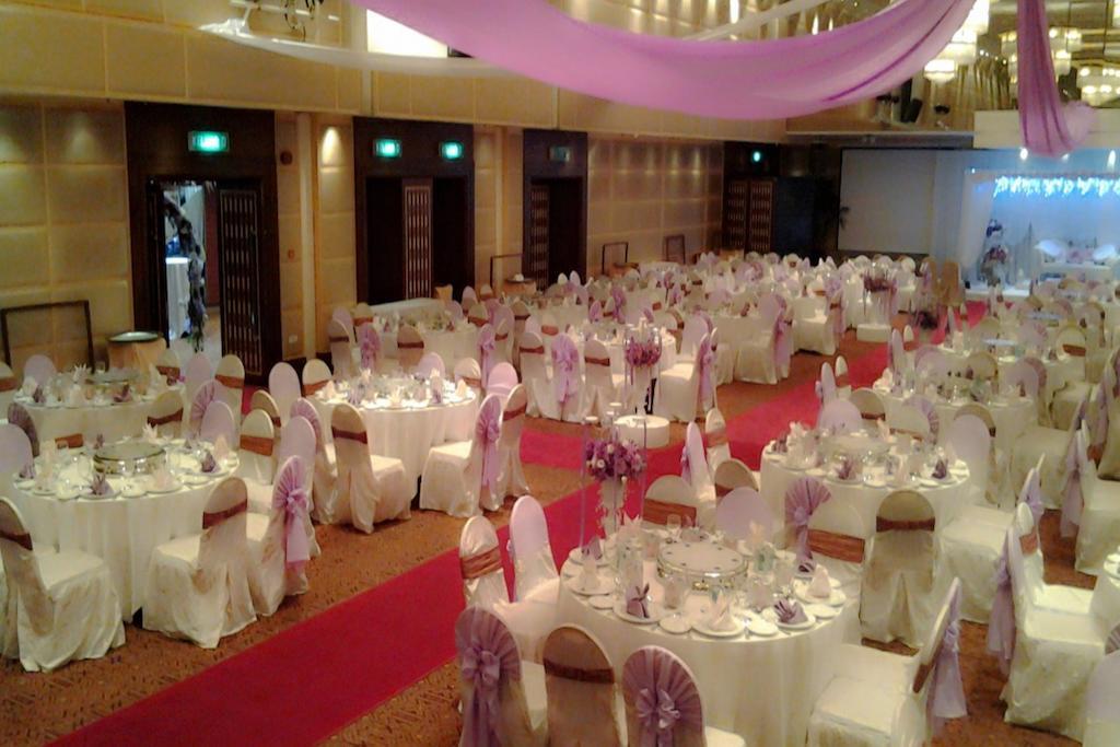 Seri Pacific Hotel Kuala Lumpur Exterior photo The photo shows a large banquet or event hall set up for a formal occasion, such as a wedding or reception. The space features multiple round tables covered in white cloths, each adorned with elegant tableware and centerpieces. The chairs are draped 