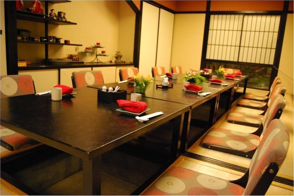 Seri Pacific Hotel Kuala Lumpur Exterior photo The photo shows an interior of a dining area that appears to be designed in a traditional style, likely inspired by Japanese aesthetics. It features a long black dining table surrounded by chairs with circular patterns on the cushions. The table is s